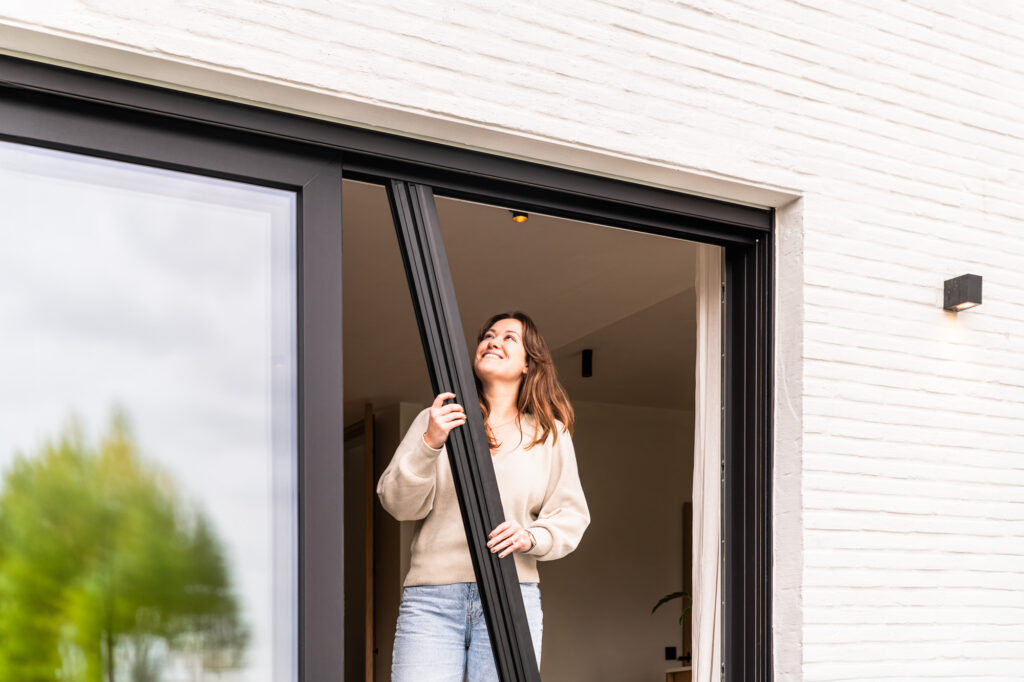 Vrouw die door een plissé hordeur stapt